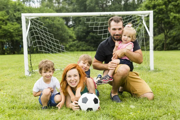 Lycklig familj med fotboll boll på ett fält — Stockfoto