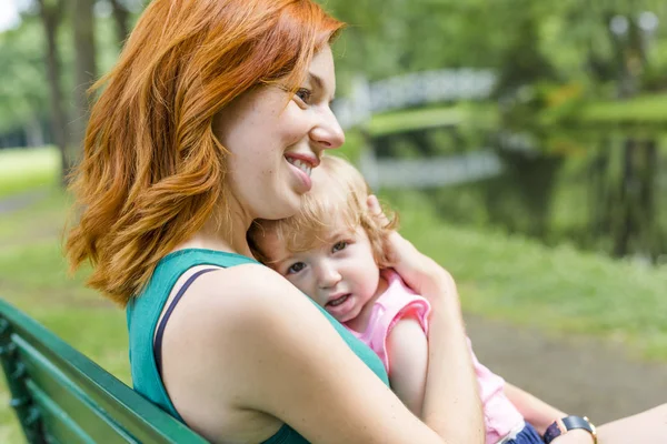 Mother and her little daughter sitting on a park bench — Stock Photo, Image