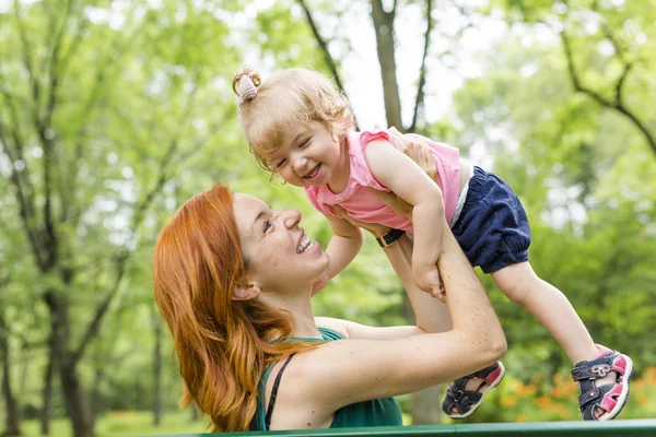 Mother and her little daughter sitting on a park bench — Stock Photo, Image