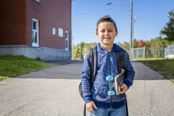 Студент поза школою стоїть посміхаючись — стокове фото