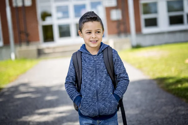 Студент поза школою стоїть посміхаючись — стокове фото