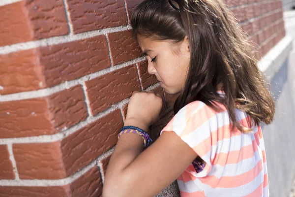 Seis anos de idade menina da escola chorar ao lado da parede de tijolo — Fotografia de Stock