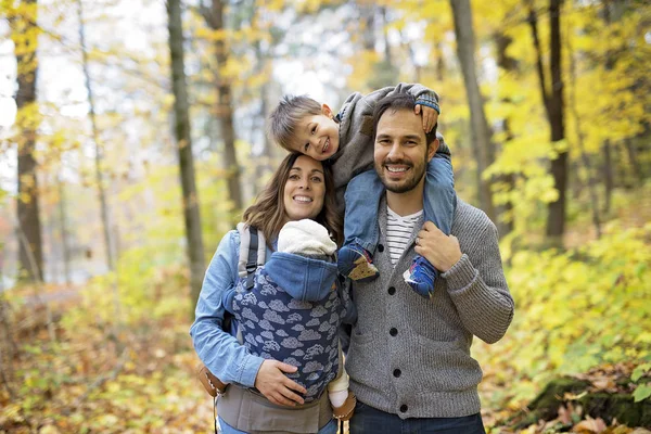 Famille de quatre personnes jouissant de feuilles dorées dans le parc d'automne — Photo