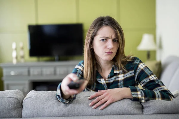 Beautiful woman watching TV sitting on couch at home — Stock Photo, Image