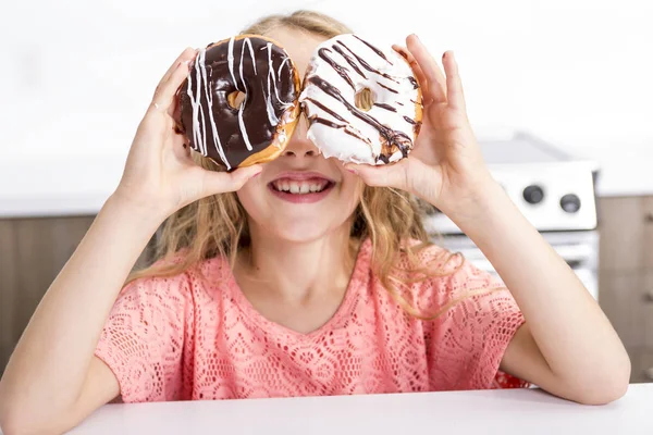 Kind spelen met donuts in haar handen persoonsgebonden op haar gezicht — Stockfoto