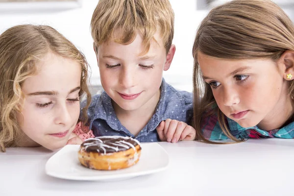 Jong kind zit op tabel horloge Donut — Stockfoto