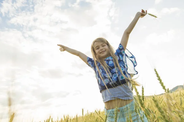 Adorable little girl playing in the wheat field on a warm summer day — Stock Photo, Image