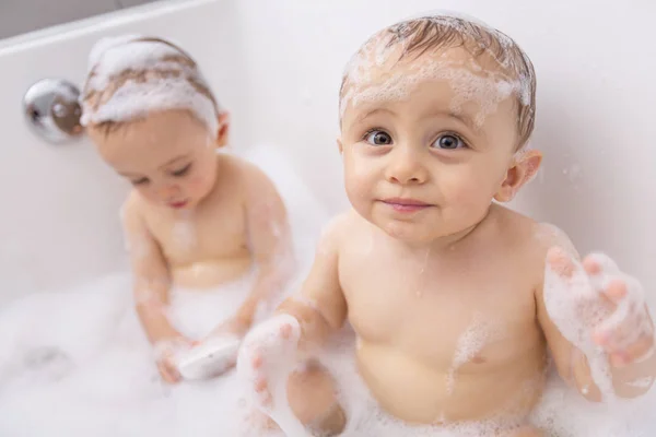 Dos niños pequeños divirtiéndose con agua tomando un baño en la bañera — Foto de Stock