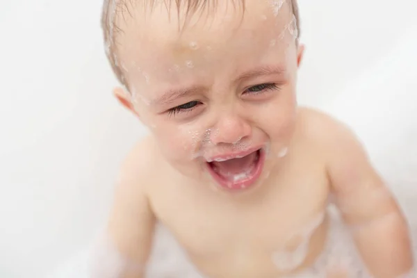 Um bebé a chorar numa banheira. Criança infantil sreaming enquanto toma um banho . — Fotografia de Stock