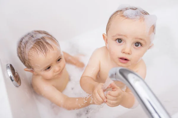 Dos niños pequeños divirtiéndose con agua tomando un baño en la bañera — Foto de Stock