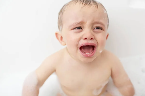 Bebé llorando en una bañera. Niño lactante gritando mientras toma un baño . — Foto de Stock