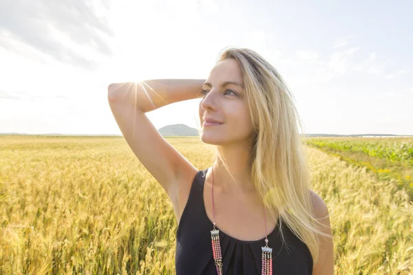 Buğday alanında duran mutlu, memnun genç kadın. — Stok fotoğraf