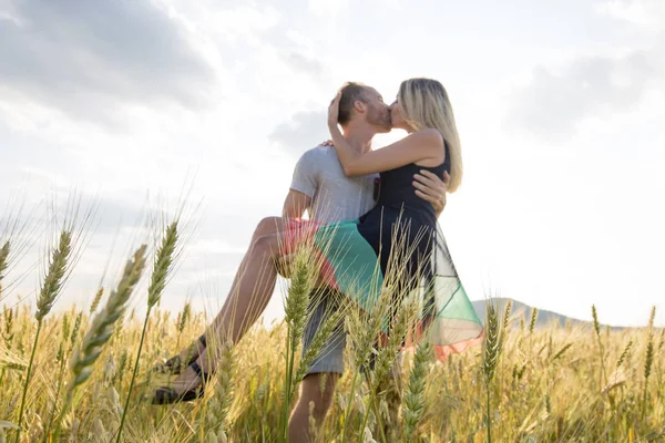 Pareja joven en un lugar romántico. Pareja enamorada al aire libre en un campo de trigo abrazando —  Fotos de Stock