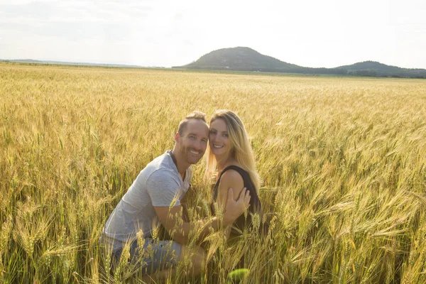 Pareja joven en un lugar romántico. Pareja enamorada al aire libre en un campo de trigo abrazando — Foto de Stock