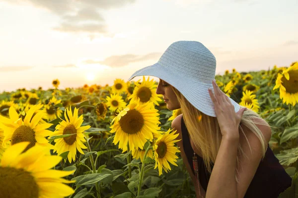 Nő kalapban, napraforgó mező naplementekor — Stock Fotó