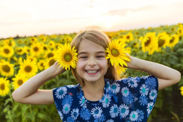 Счастливая девушка на поле подсолнухов на летнем закате — стоковое фото