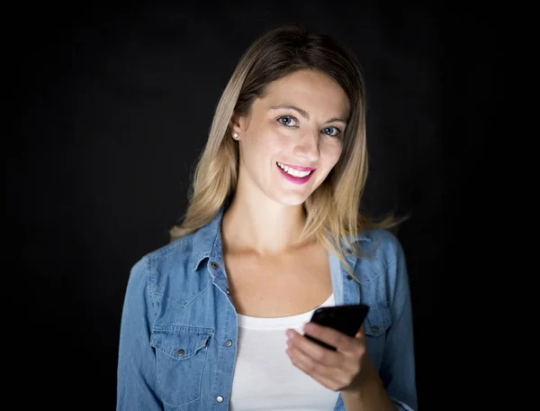 Closeup of woman holding and using modern smart phone on black background — Stock Photo, Image