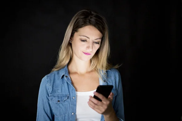 Closeup of woman holding and using modern smart phone on black background — Stock Photo, Image