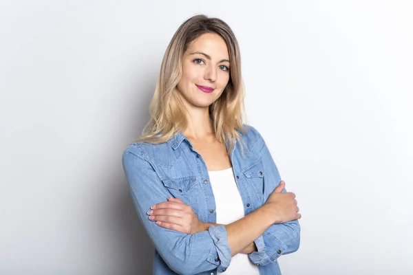 Ung kvinna i Jeansskjorta och Jeans, lutad mot grå vägg bakgrund — Stockfoto