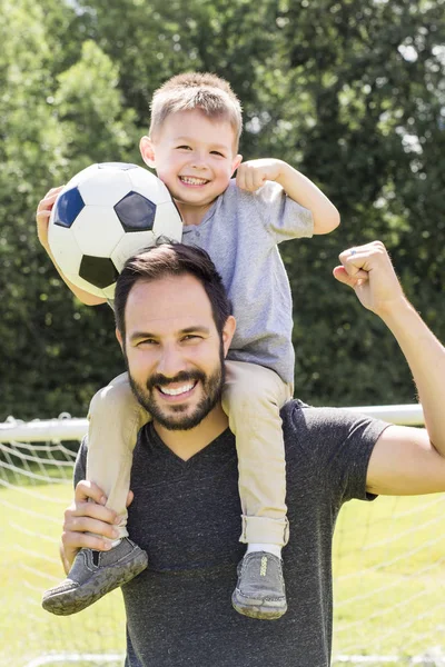 Joven padre con su pequeño hijo jugando fútbol en el campo de fútbol —  Fotos de Stock