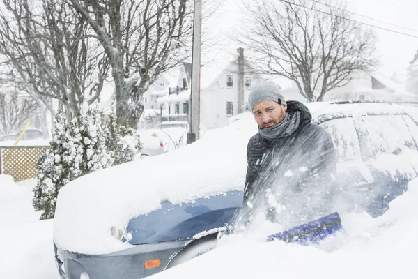 彼の車のフロント ガラスの雪を磨く男 — ストック写真