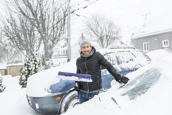 彼の車のフロント ガラスの雪を磨く男 — ストック写真