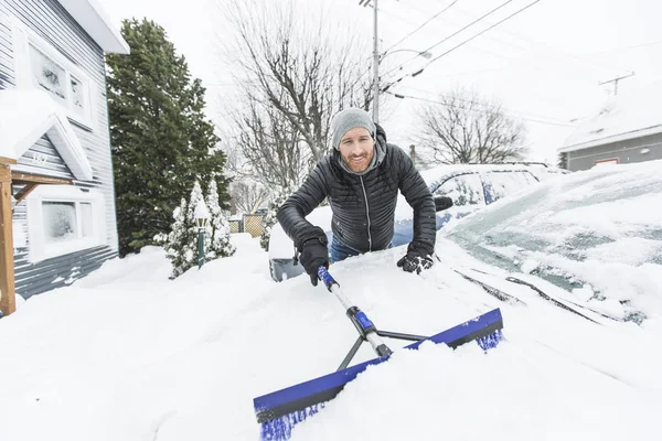 彼の車のフロント ガラスの雪を磨く男 — ストック写真