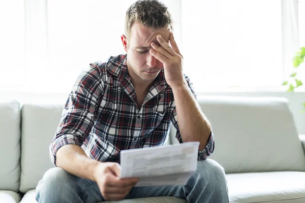 Shocked man holding some documents on sofa livingroom — Stock Photo, Image