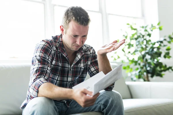 Shocked man holding some documents on sofa livingroom — Stock Photo, Image