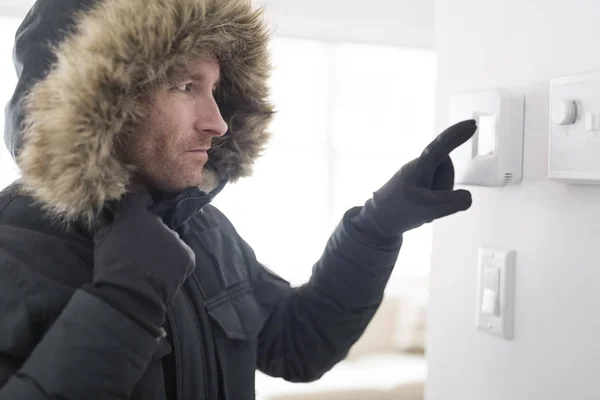 Человек в теплой одежде чувствует холод внутри дома — стоковое фото