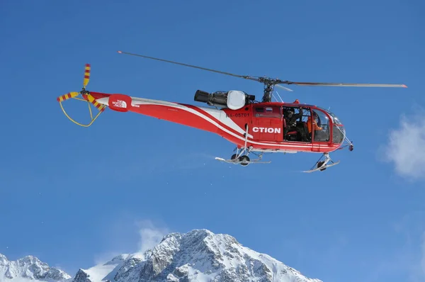 Karlı dağların üzerinde kırmızı helikopter