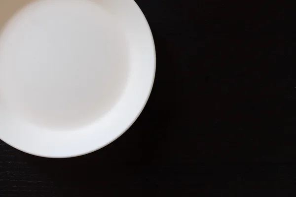 Siyah ahşap masada boş beyaz tabak — Stok fotoğraf