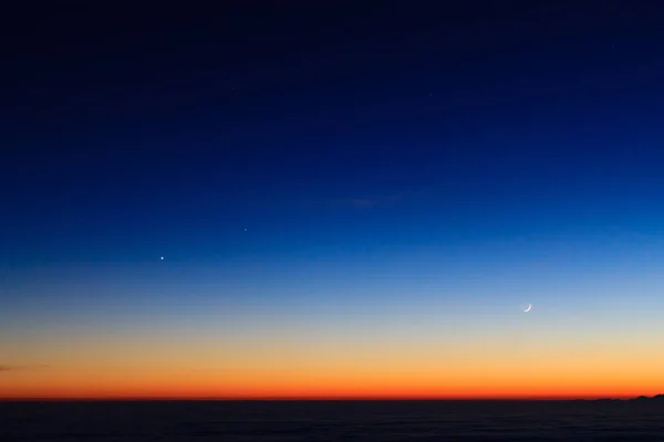 Silueta de montaña sobre nubes, cielo al atardecer con luna — Foto de Stock