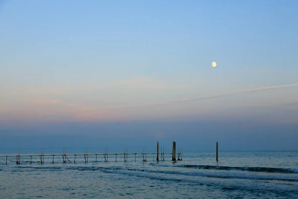 Пляжный пейзаж на рассвете с луной — стоковое фото