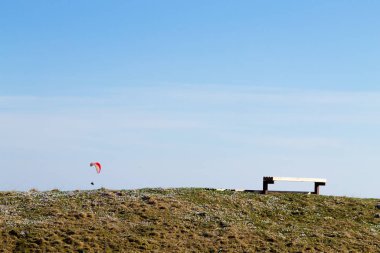 Ön planda boş bank ile mavi gökyüzünde Yamaç paraşütü