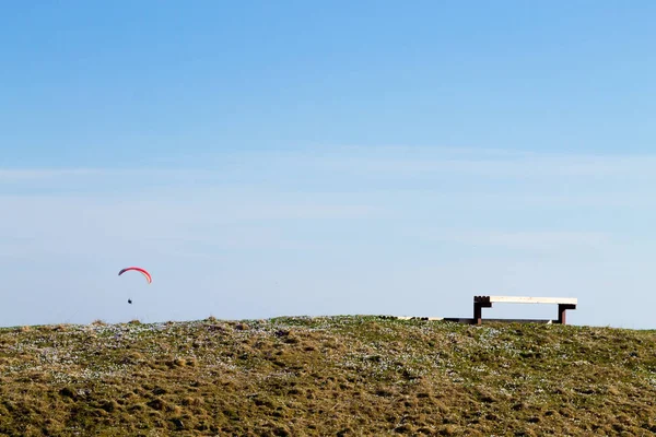 Paraglider på blå himmel med Tom bänk på förgrunden — Stockfoto