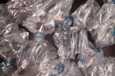 Plastik şişelerin arka planı. Siyah yüzeyde boş şişeler. Geri dönüşümsüz atık