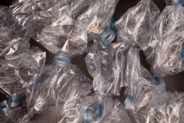 Plastik şişelerin arka planı. Siyah yüzeyde boş şişeler. Geri dönüşümsüz atık