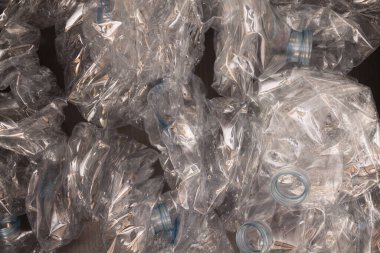 Plastik şişelerin arka planı. Siyah yüzeyde boş şişeler. Geri dönüşümsüz atık