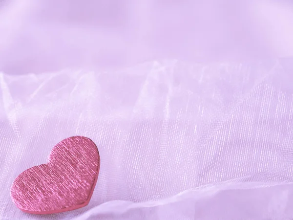 Pink heart on a pink textile background