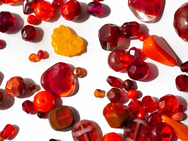 Sparkling colorful beads in various red colors in detail on white background