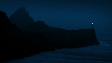 Gece Rocky kıyısındaki deniz feneri