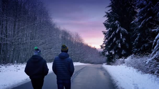 夕暮れ時の雪に覆われた森の中を歩く人々 — ストック動画