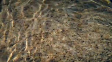 Güneş ışığı dalgalanan fazla nehir taşı