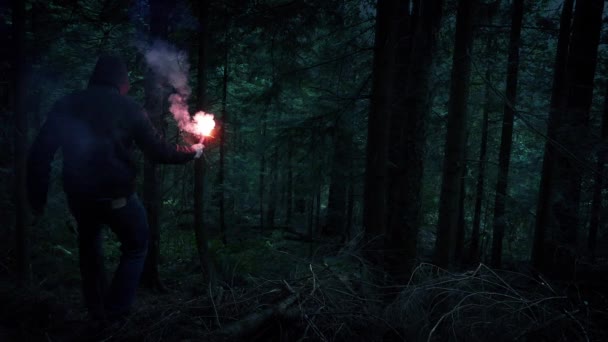 L'homme à la fusée éclairante descend la pente forestière — Video