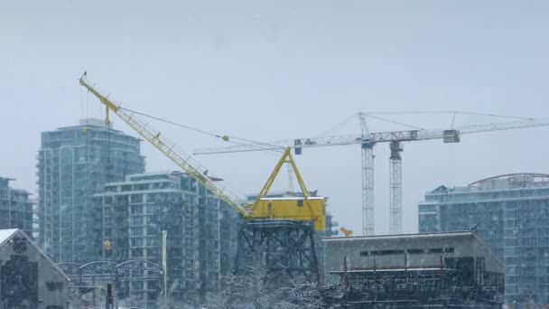 Grúas grandes en la ciudad con nieve cayendo — Vídeos de Stock