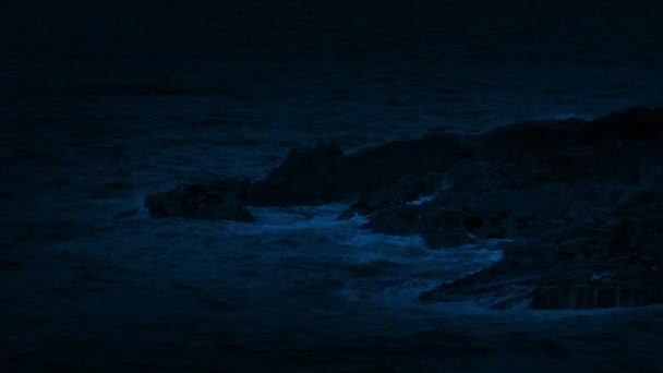 Vagues océaniques se brisant sur les rochers la nuit 