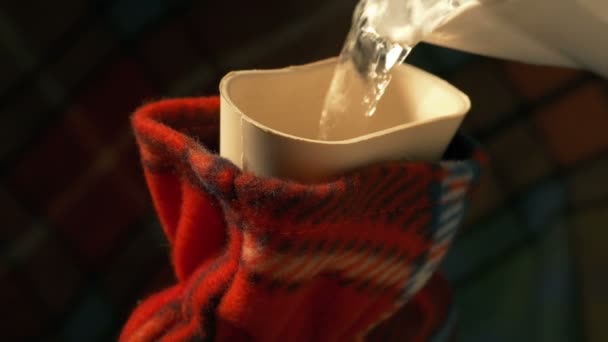 Bouilloire verse dans une bouteille d'eau chaude 