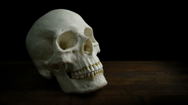 テーブルの上で人間の頭蓋骨を渡す — ストック動画