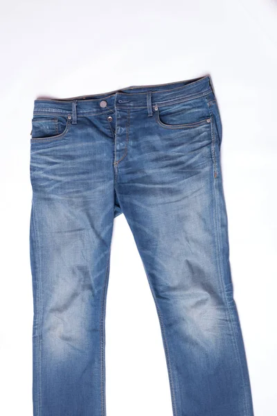 Сині джинси лежать на білому тлі — стокове фото